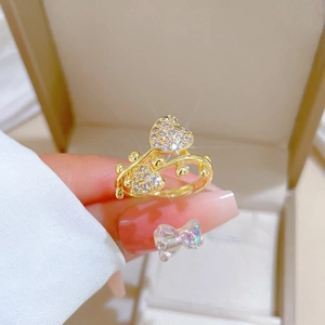 Detail of hand wearing gold double heart ring with pavé zircons on beige jewelry box