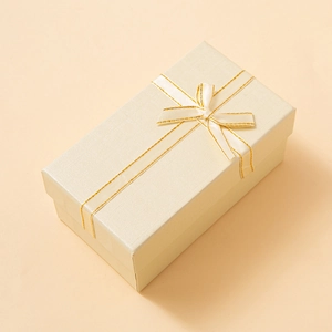 Elegant champagne rectangular jewelry gift box with a silk ribbon bow and fine texture