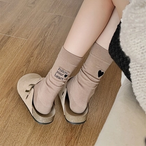 Detail of beige cotton socks featuring Follow your heart embroidery and black heart pattern