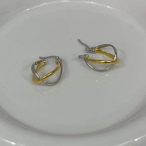 Detail of two-tone silver and gold twisted hoop earrings on a white ceramic plate