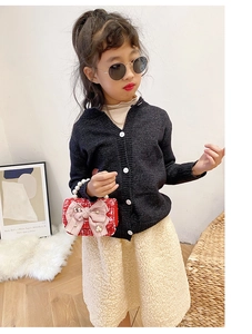 Detail of a black V-neck knitted cardigan with white buttons for girls' fashion style