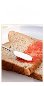 Gros plan d'un couteau à beurre en acier étalant de la confiture sur du pain