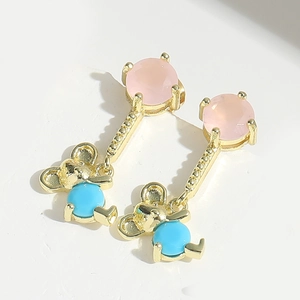 Detailed close-up of golden bear earrings with pink and blue stones on white background