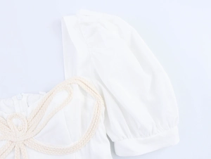 Close-up of white princess style dress with bubble sleeves and woven knot detail