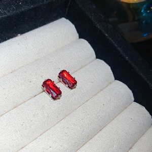 Detailed view of red rectangular zircon earrings with silver-tone prong setting on display