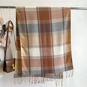 Detailed view of checkered autumn scarf with fringe tassels in warm caramel and beige tones