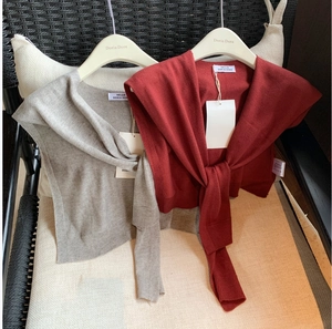 Detail of grey and red wool blend knitted shawls with tie-front on professional hangers