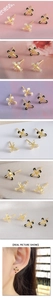 Detailed view of minimalist cross stud earrings in gold with black and white accents