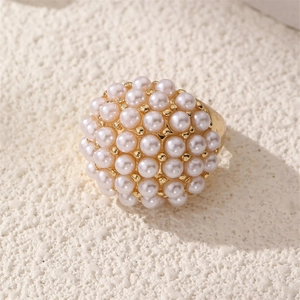 Macro shot of cluster pearl cocktail ring with glossy gold metal setting on stone