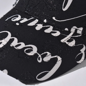 Close-up of black cotton baseball cap with white cursive lettering and heart embroidery