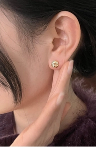 Primer plano detallado de pendientes dorados minimalistas de estilo retorcido en modelo