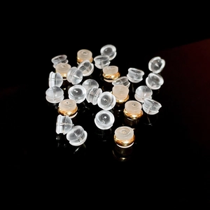 Macro shot of transparent silicone earring backs scattered on a black reflective surface