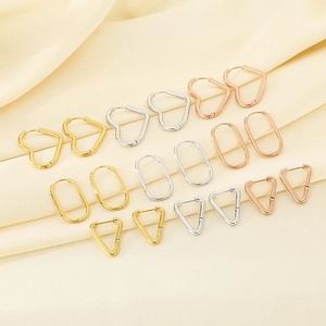 Close-up of geometric heart, oval and triangle earrings in gold, silver and rose gold