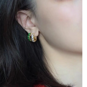 Gold plated brass huggie earrings with emerald green and white zircon stones on model