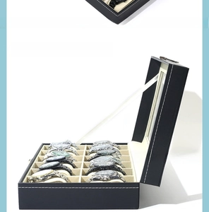 Detail view of 12-slot black leather watch box with clear window and velvet interior