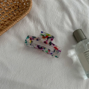 Detail of a medium acetate hair claw with colorful abstract ink patterns and polished finish