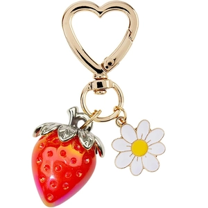 Detail of strawberry charm with white daisy pendant and golden heart-shaped clasp