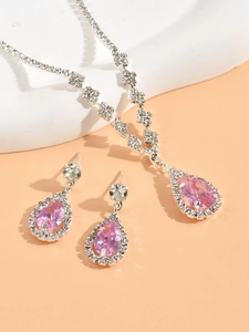 Close-up of silver necklace and earrings set with pink pear-shaped stones and crystals