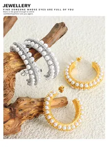 Macro shot of gold and silver C-shaped hoop earrings with pearls on driftwood