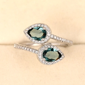 Macro shot of silver bypass ring with pear-cut dark green stones and micro-pave crystals