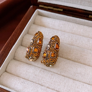 Gros plan de boucles d'oreilles vintage avec strass ambre et champagne sertis d'or