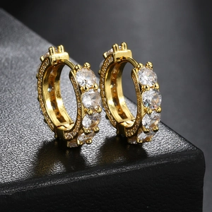Detailed close-up of golden iced-out hoop earrings with micro-paved white zircon stones