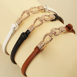 Detailed close-up of slim leather belts in white, black, and brown with gold woven buckles
