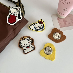Detailed view of white cartoon cat plush brooches with embroidery and metal safety pins