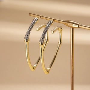Detail of gold heart earrings with sparkling crystals on a bamboo-style metal stand