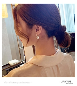 Detail of elegant gold hoop earrings with white pearl pendants worn by a model