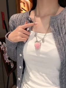 Close-up of pink flocked strawberry pendant with silver beaded chain on female neck