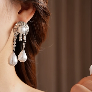 Detail of silver drop earrings with white pearls and sparkling rhinestones on model