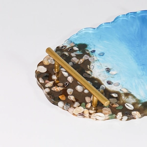 Detail of blue ocean resin tray featuring real seashells and gold metal handles