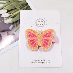 Detailed view of handmade glittery butterfly hair clip on white packaging card
