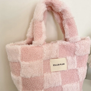 Close-up of pink checkered plush tote bag with embroidered label and soft texture