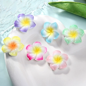 Macro view of gradient colorful resin frangipani flower charms on white display plate
