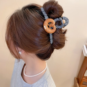 Détail d'une pince à cheveux rayée noir et blanc avec ornement bretzel en résine