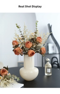 Detailed close-up of retro rose and daisy faux floral arrangement in white ceramic vase