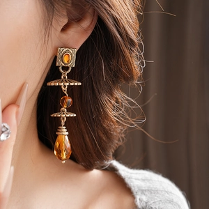 Close-up of vintage gold earrings with amber beads and water drop pendants on model