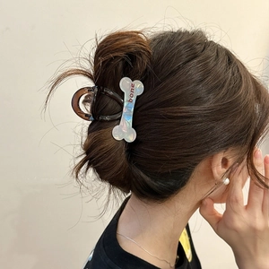 Chic bone-shaped dog claw clip in pearly white and coffee brown worn by a model