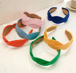 Top view of handmade braided raffia headbands in six vibrant colors on white background