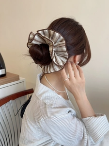 Detail of large striped fabric scrunchie in brown and beige on a bun hairstyle