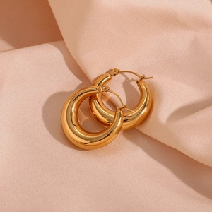 Detailed view of 18K gold plated 25mm hollow hoop earrings on soft pink satin fabric