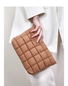 Close-up of brown quilted puffer clutch bag with gold zipper and textured padding