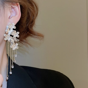 Detail of layered flower earrings with metal chain tassels and crystal pendants on model