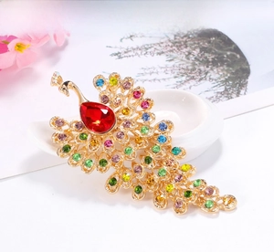 Detailed close-up of a peacock brooch with colorful crystals and a red teardrop gem