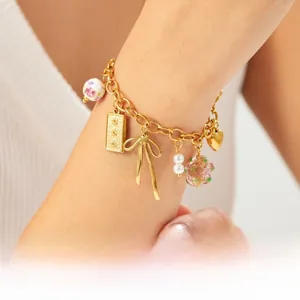 Vue macro du bracelet à maillons dorés avec perles en céramique et multi-pendentifs