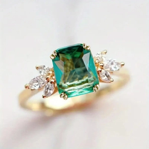 Macro detail of emerald-cut green gemstone ring with marquise zircon stones and gold band