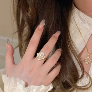 Close-up of gold-plated four-leaf clover necklace and ring set with white mother of pearl