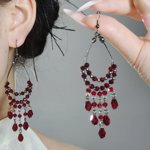 Detail of vintage chandelier earrings with dark red beads and crystal water drop tassels
